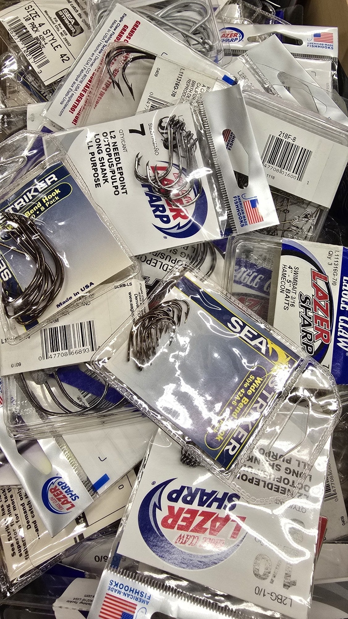Assorted fishing hooks — Eagle Claw, Sea Striker and more in a store bin